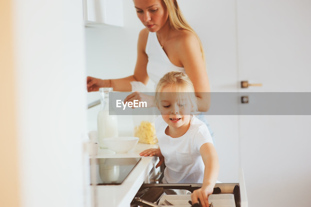 Mother with daughter preparing food in kitchen at home