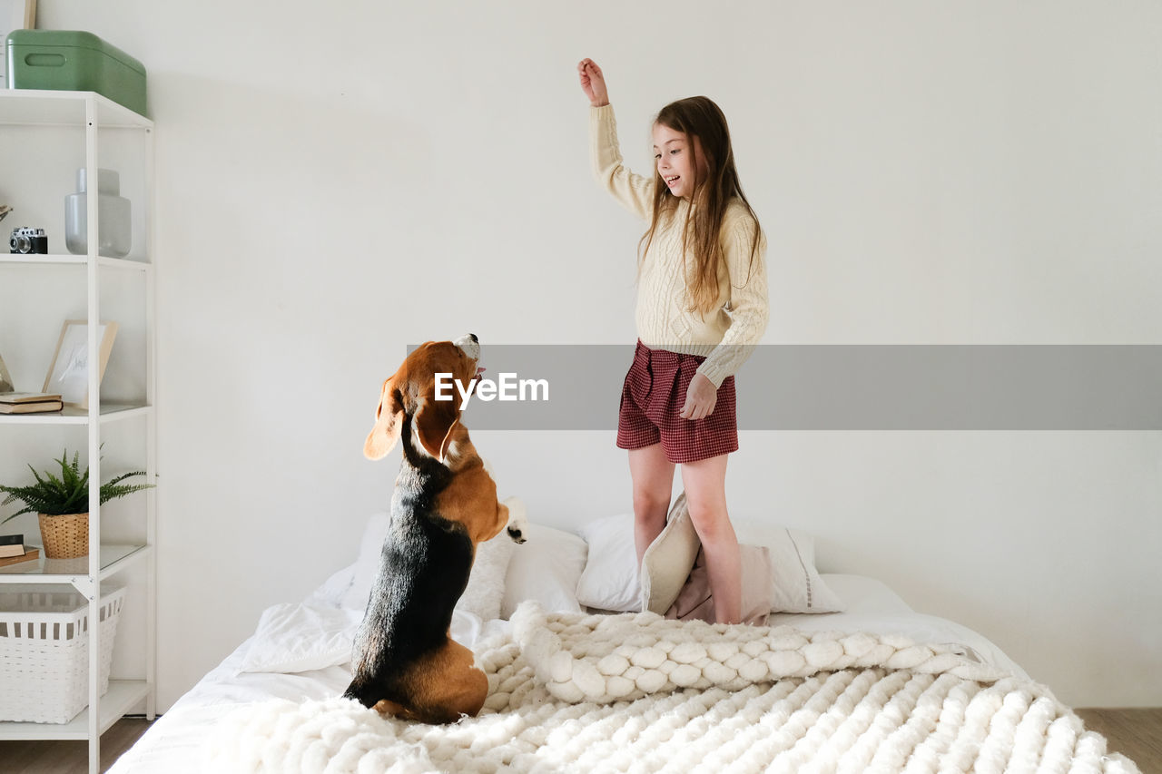 Girl playing with dog on bed at home