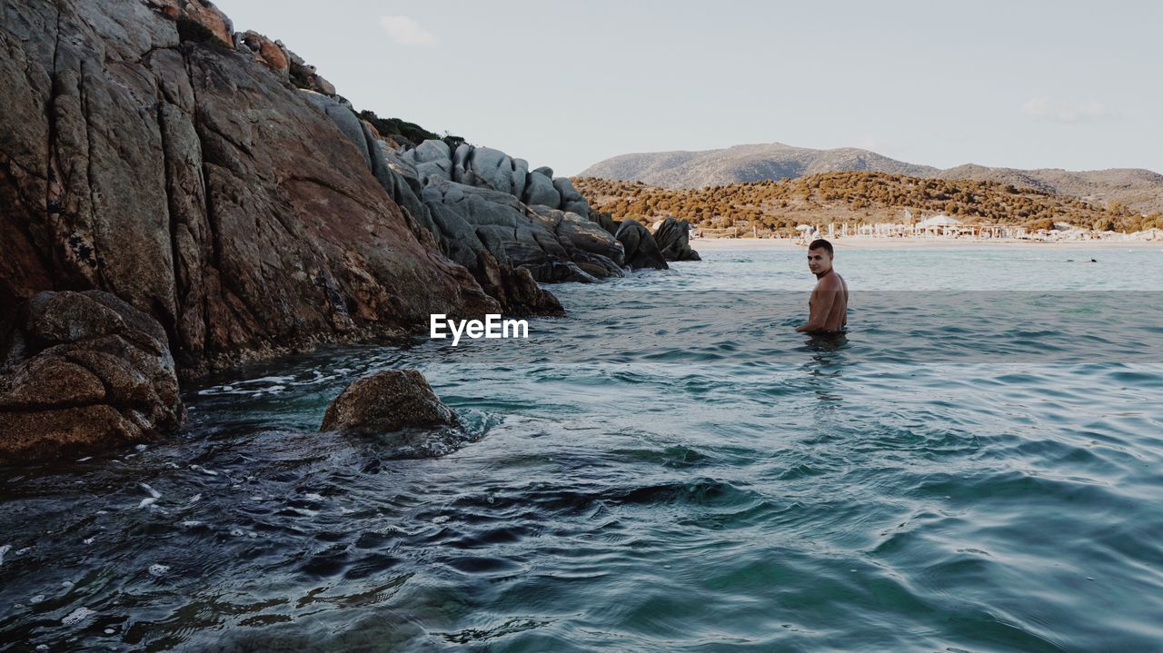 Side view of shirtless man swimming in sea