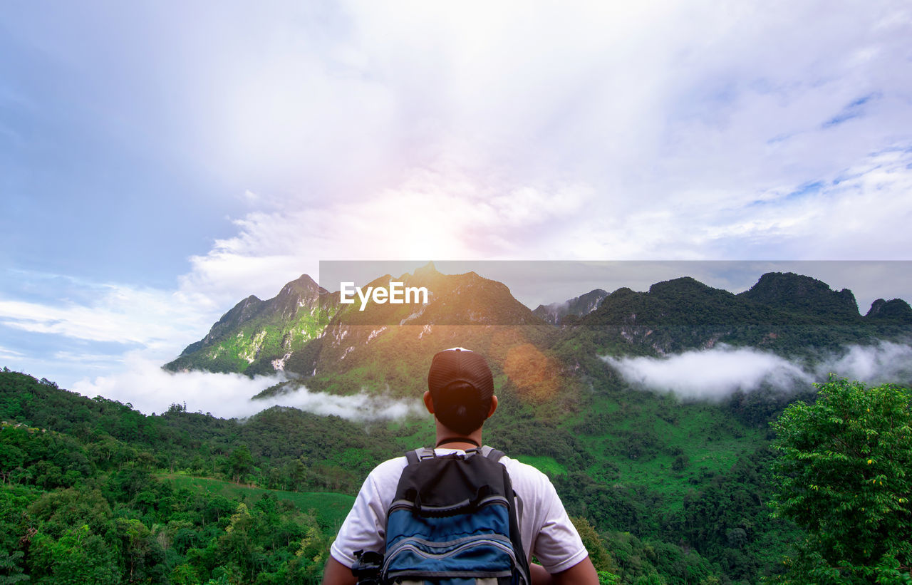 REAR VIEW OF MAN LOOKING AT MOUNTAINS