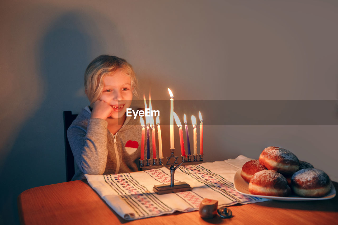 Girl lighting candles on menorah for traditional jewish hanukkah holiday. child celebrating chanukah