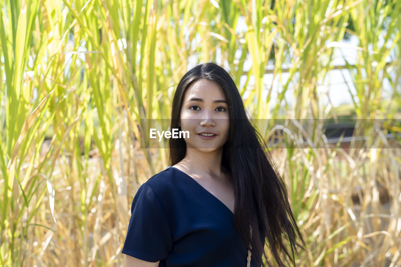 Portrait of young woman standing against plants