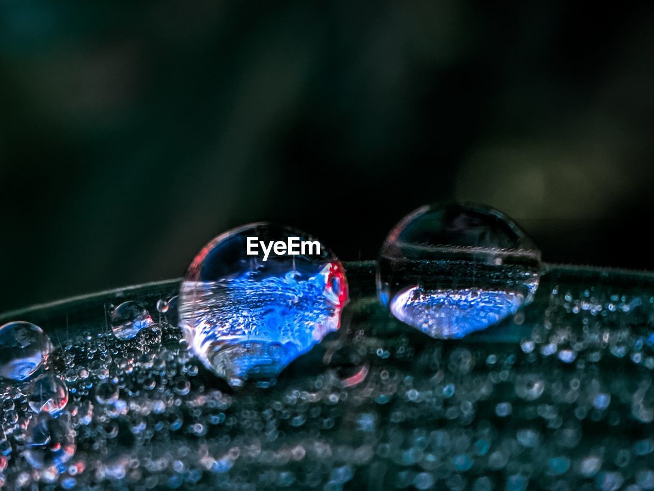 CLOSE-UP OF WET GLASS AGAINST BLUE BACKGROUND