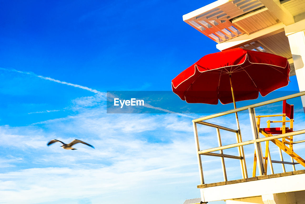 LOW ANGLE VIEW OF RED UMBRELLA AGAINST BLUE SKY