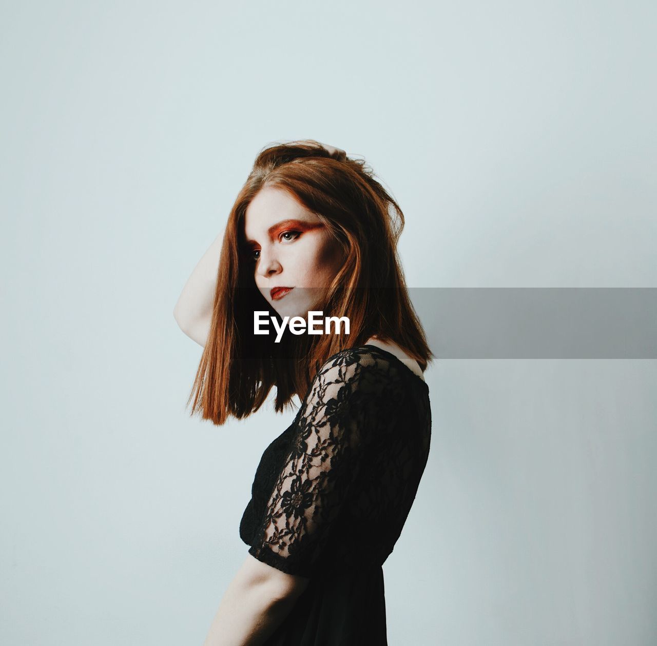 Side view of young woman standing against white background