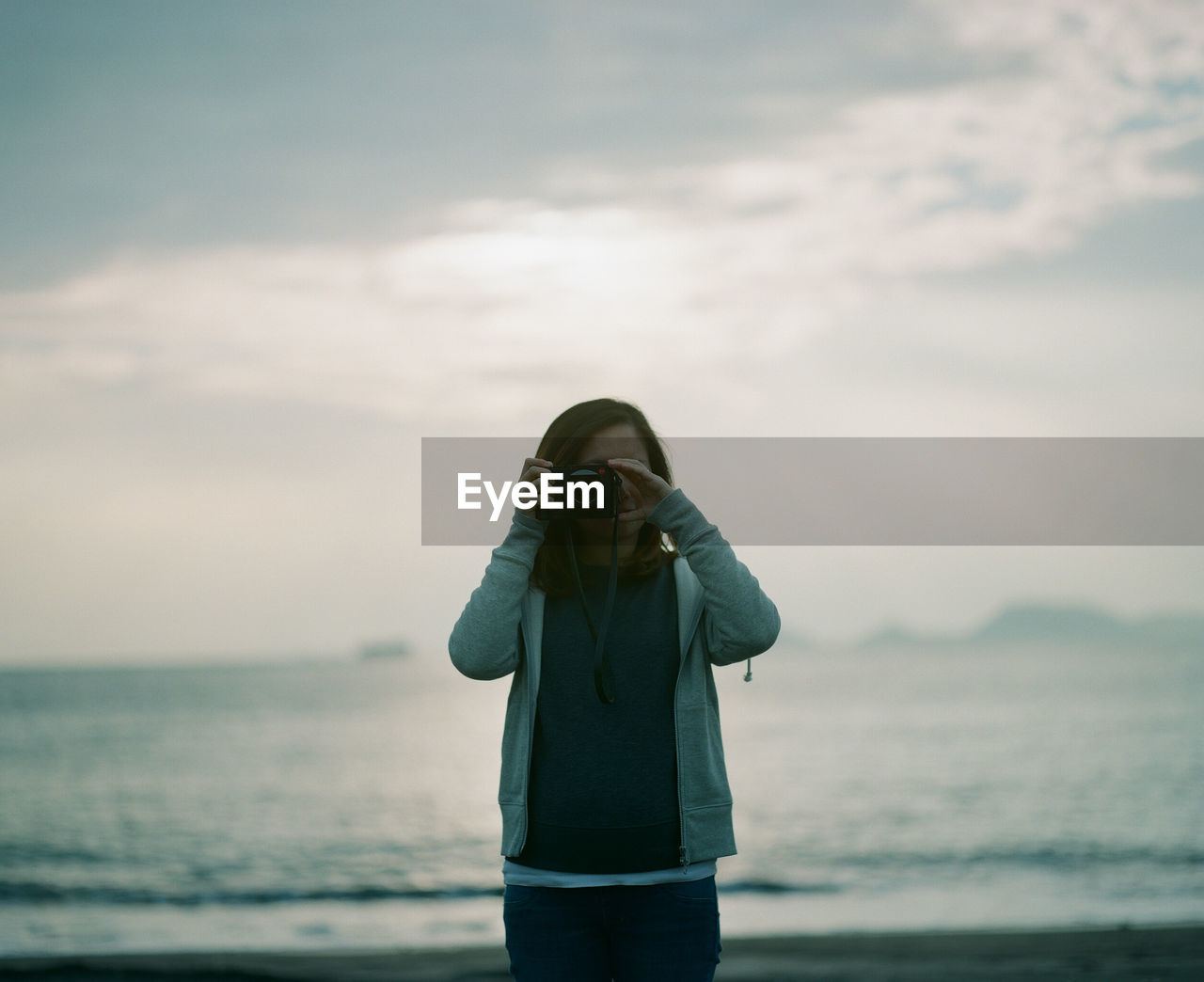 Woman photographing with camera against sea and sky