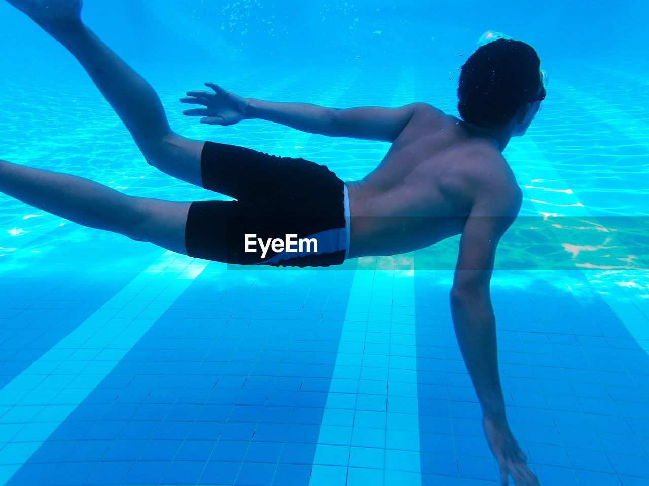 Shirtless teenage boy swimming in pool