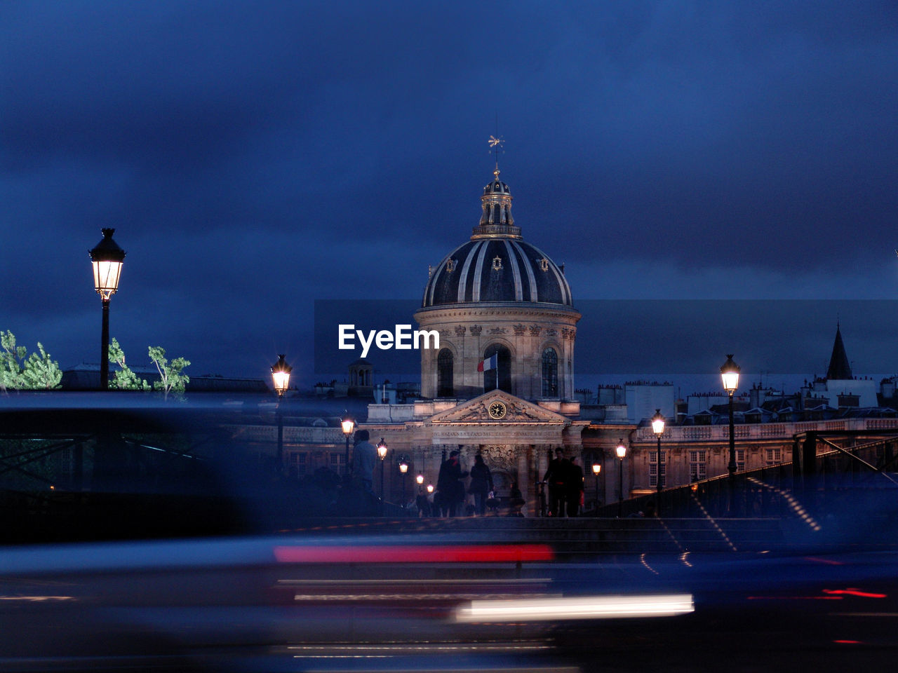 Light trails against institut de france and cloudy sky at dusk