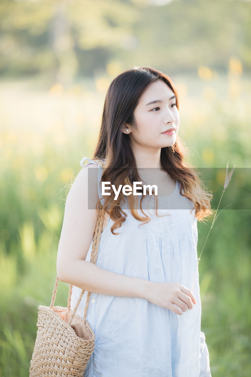 Smiling young woman standing on land