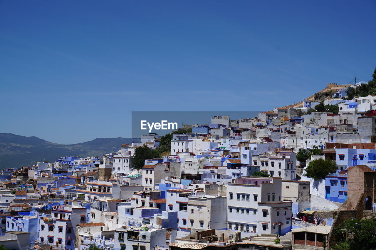 Houses in town against clear blue sky