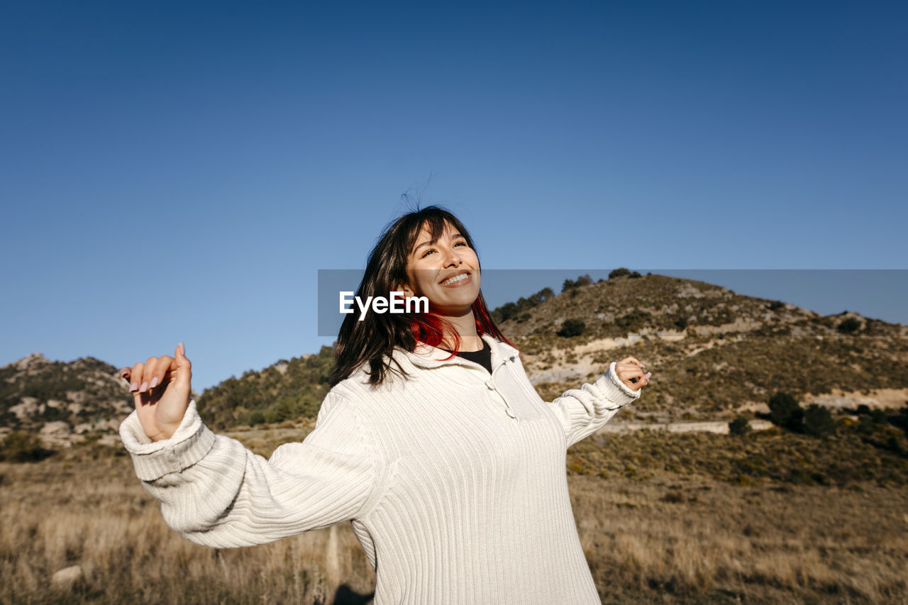 Smiling woman with arms outstretched on mountain