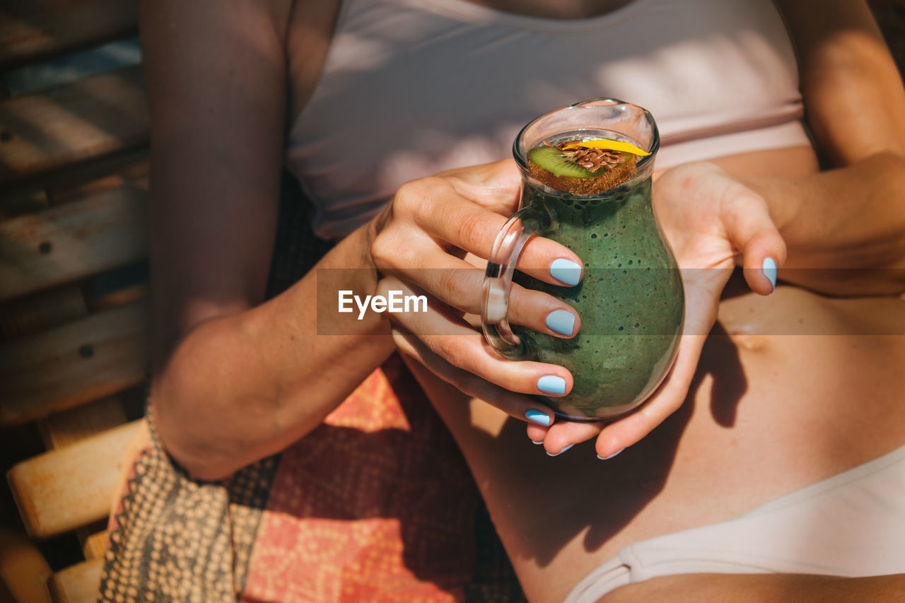 Midsection of woman holding drink in container