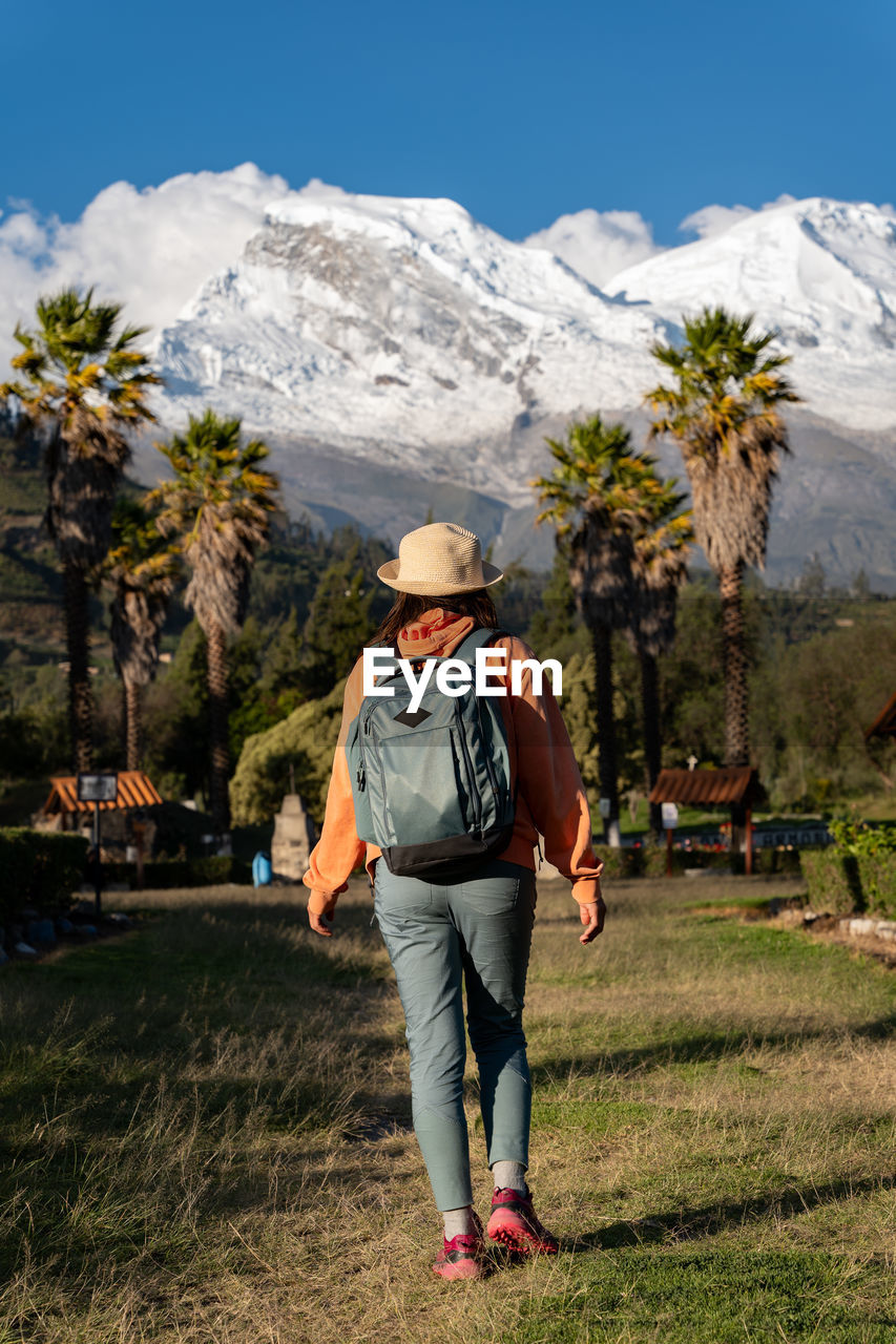 Tourist walks through the town named yungay with the snow-capped huascaran in the background.