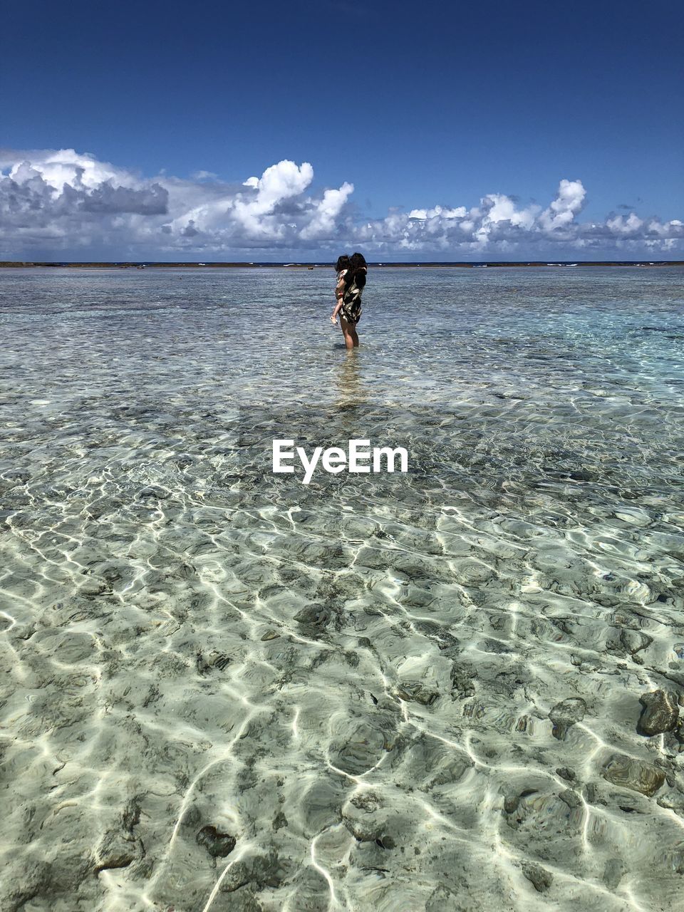 Full length of woman with girl standing in sea against sky