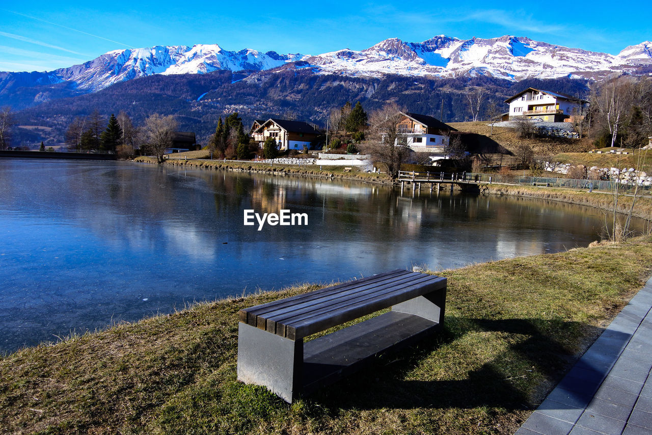 Scenic view of lake by snowcapped mountains against sky