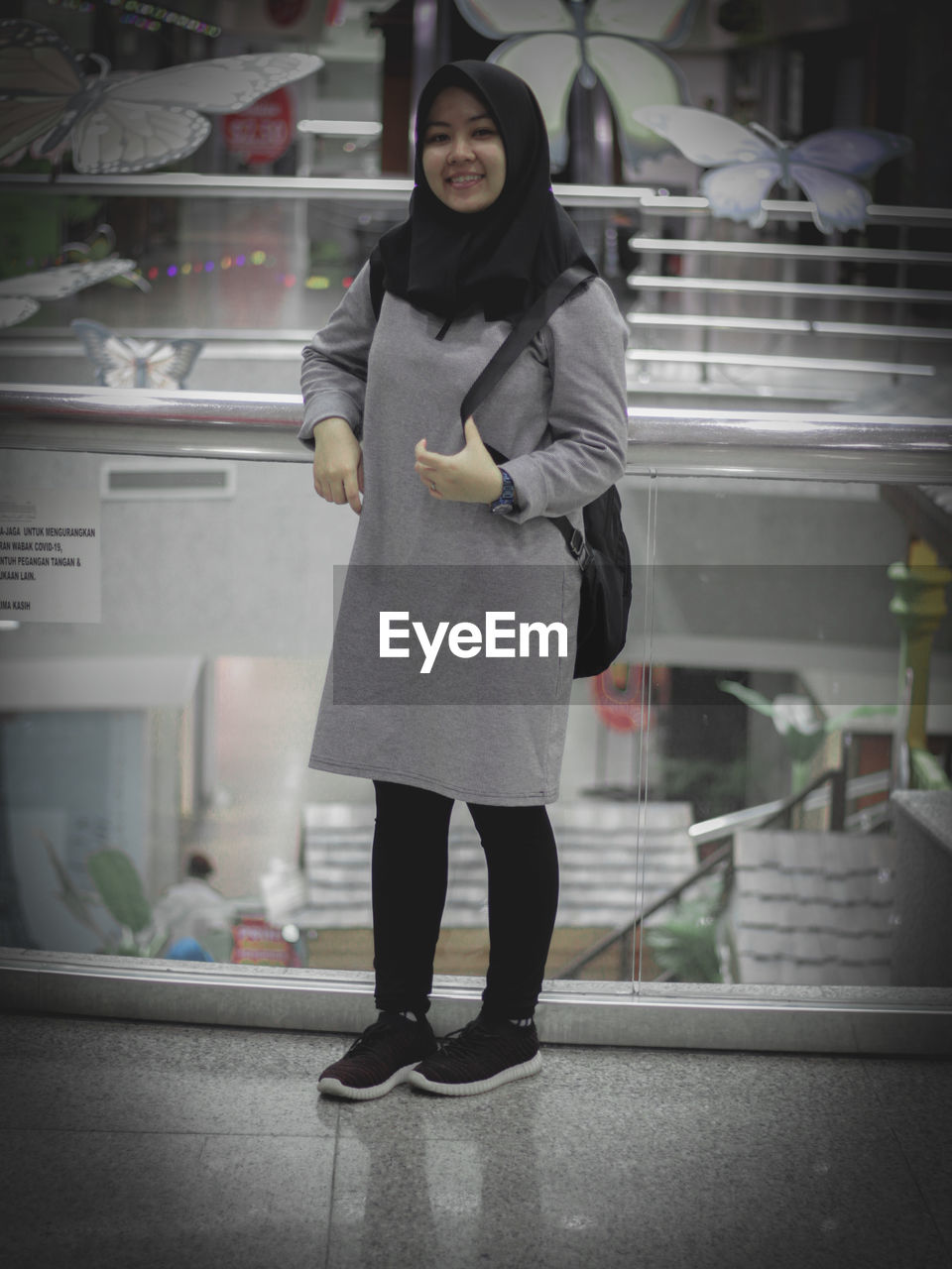 FULL LENGTH PORTRAIT OF A WOMAN STANDING AGAINST BUILDING