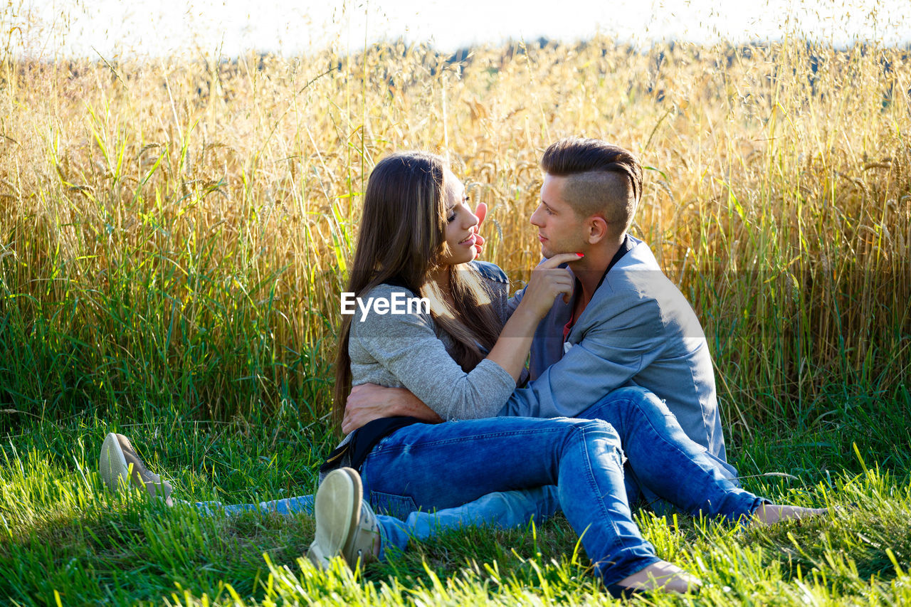 COUPLE SITTING ON FIELD