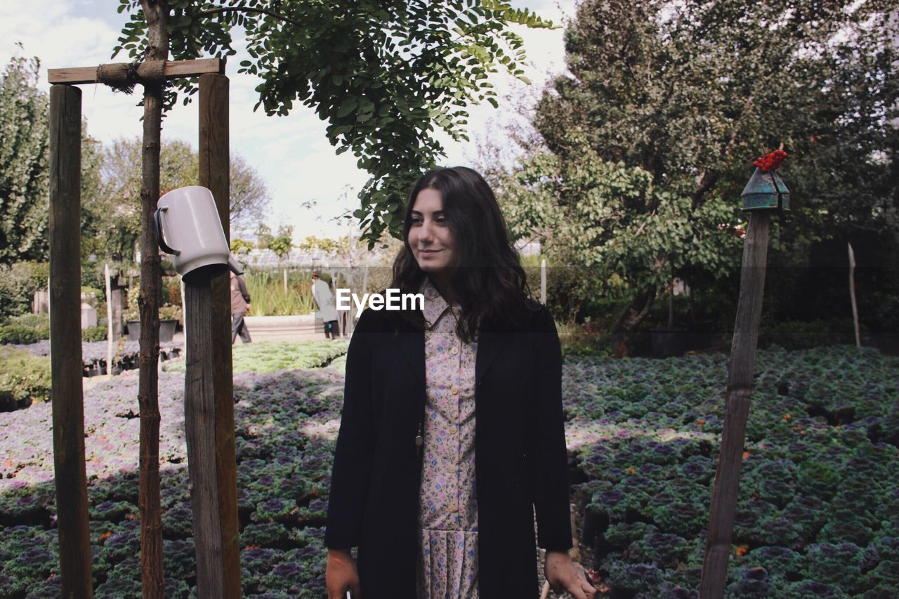 Smiling young woman standing against trees