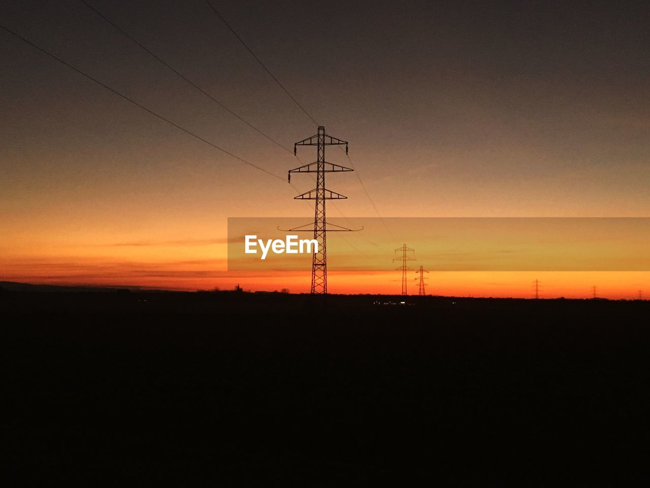 Low angle view of silhouette electricity pylon against sky during sunset