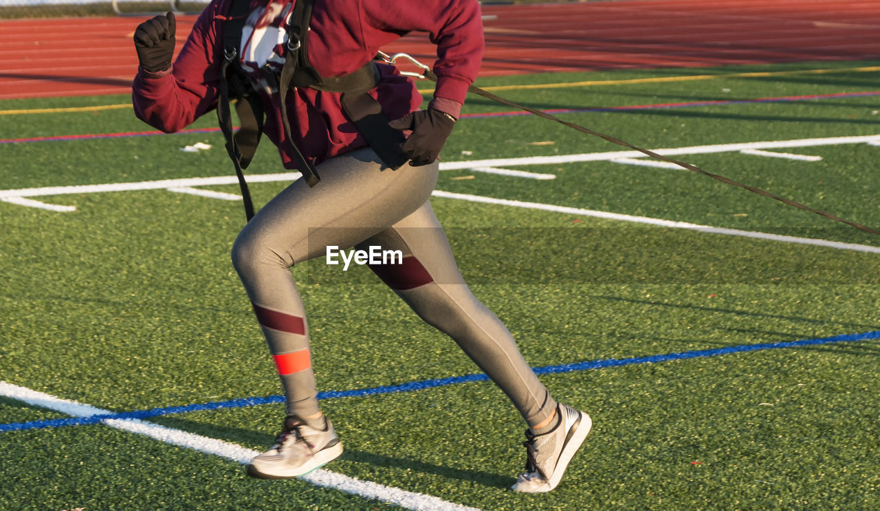 Low section of woman running on soccer field