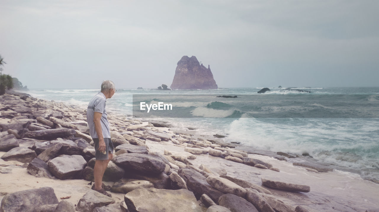 MAN LOOKING AT SEA SHORE