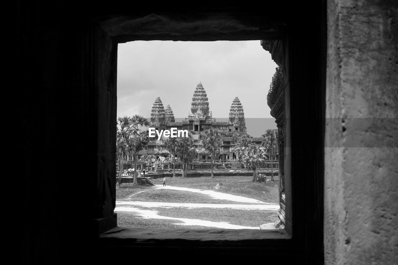 Buildings and temple in angkor wat cambodia against sky seen through window. 