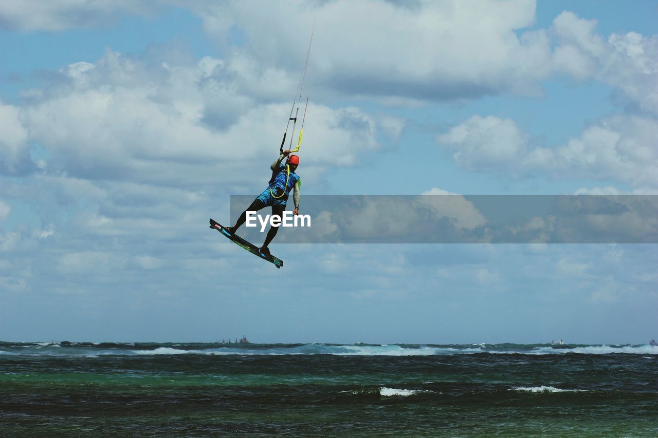 low angle view of woman jumping on beach against sky