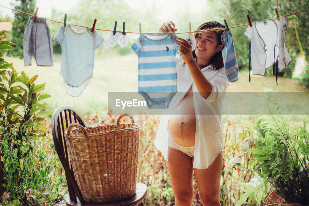 Pregnant woman hanging baby clothes on clothesline