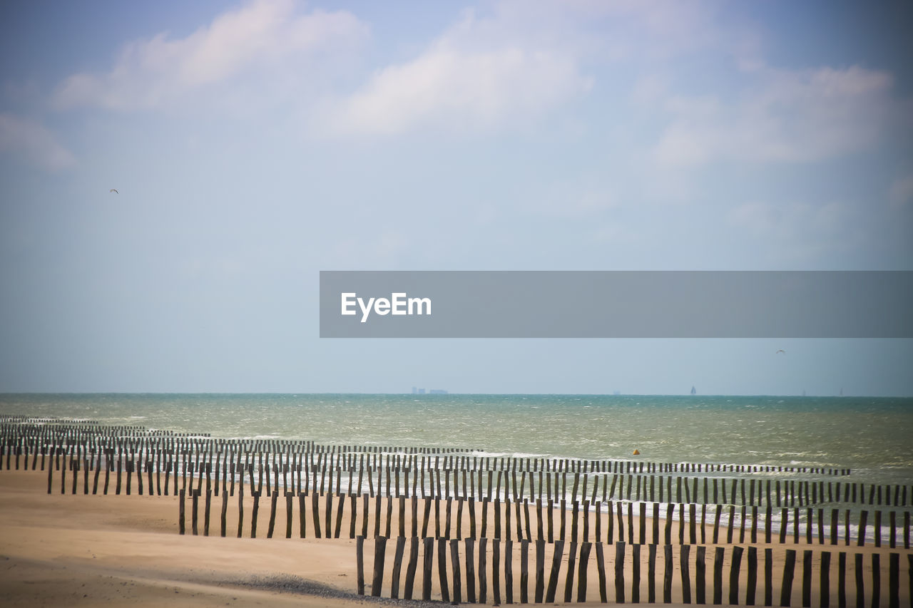 Wooden posts on beach against sky