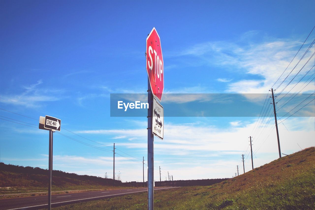 Low angle view of road sign against blue sky