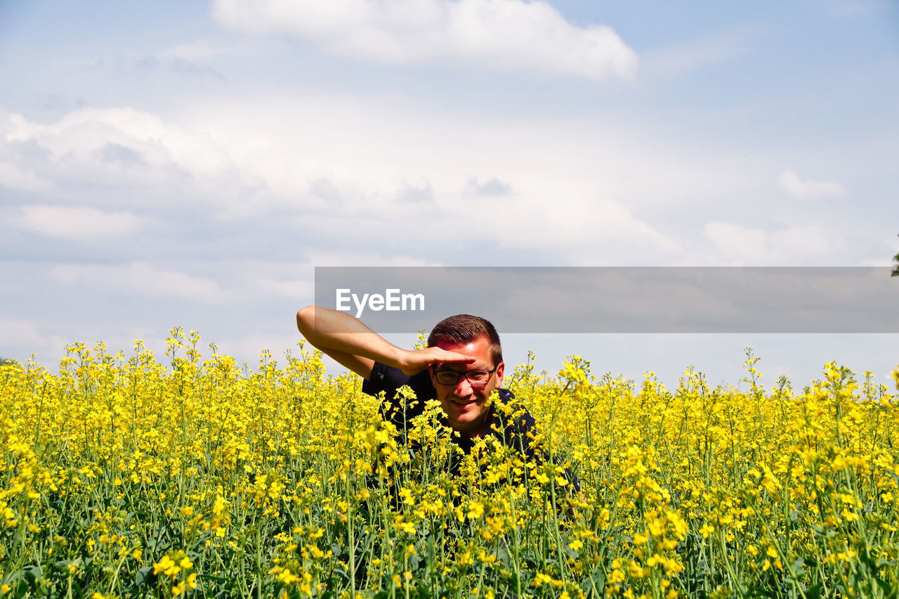 Portrait of smiling mid adult man in oilseed rape field