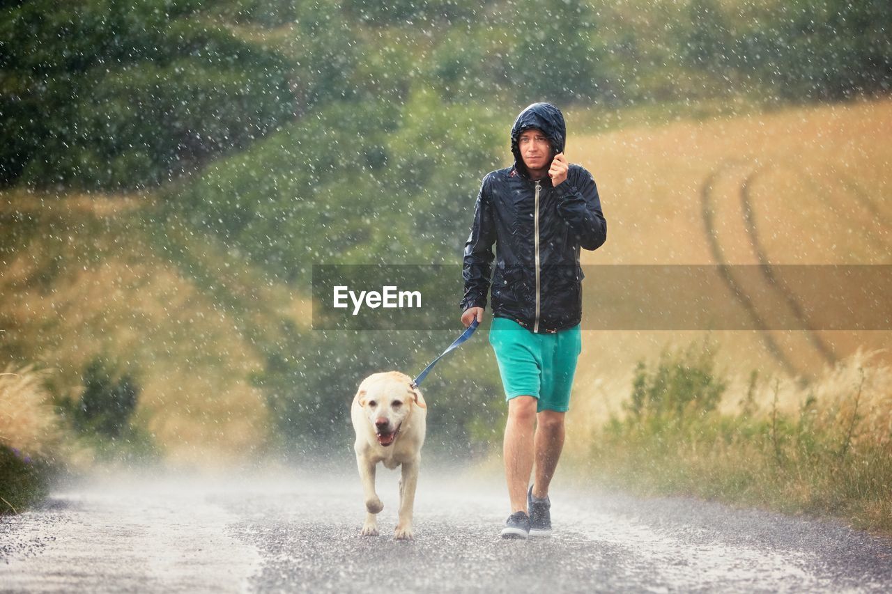 Man walking with dog on road during rainy season