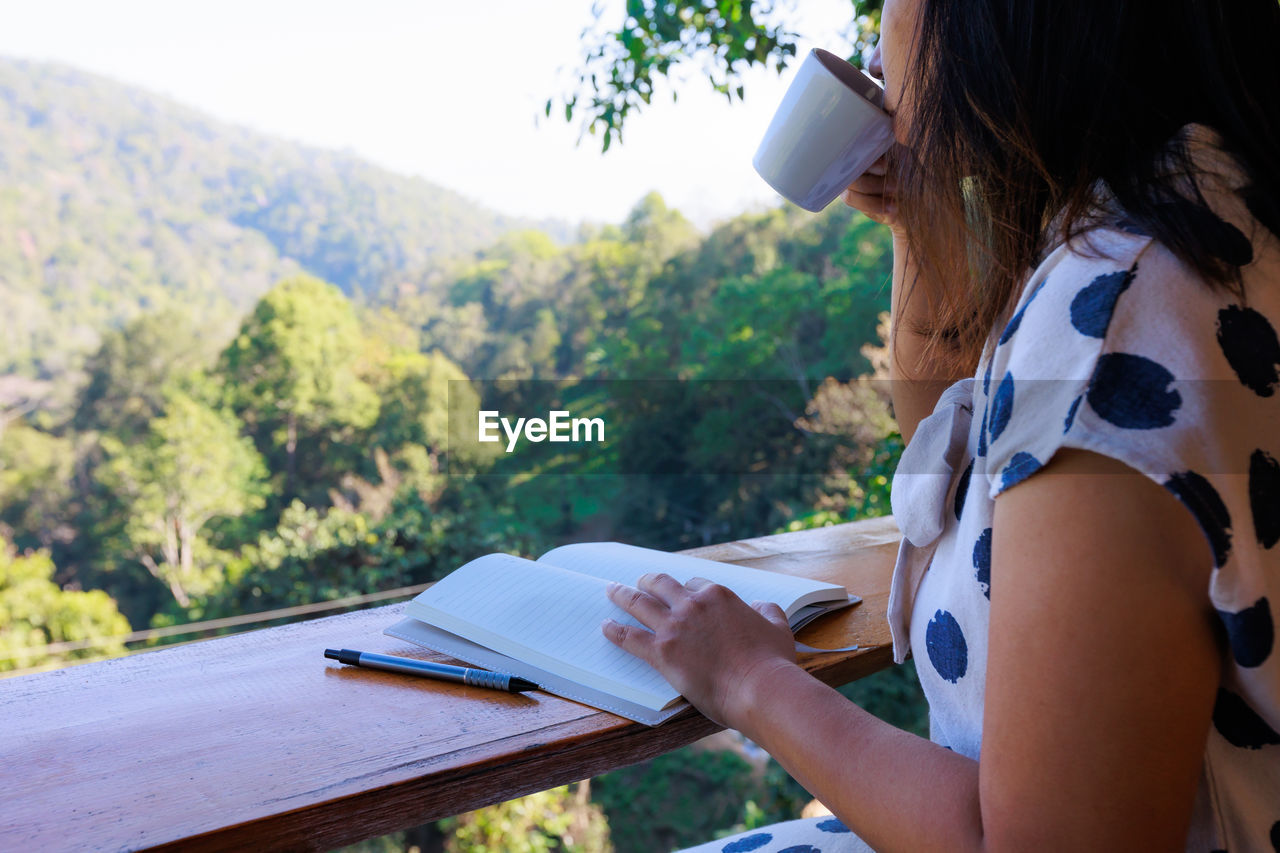 side view of young woman reading book