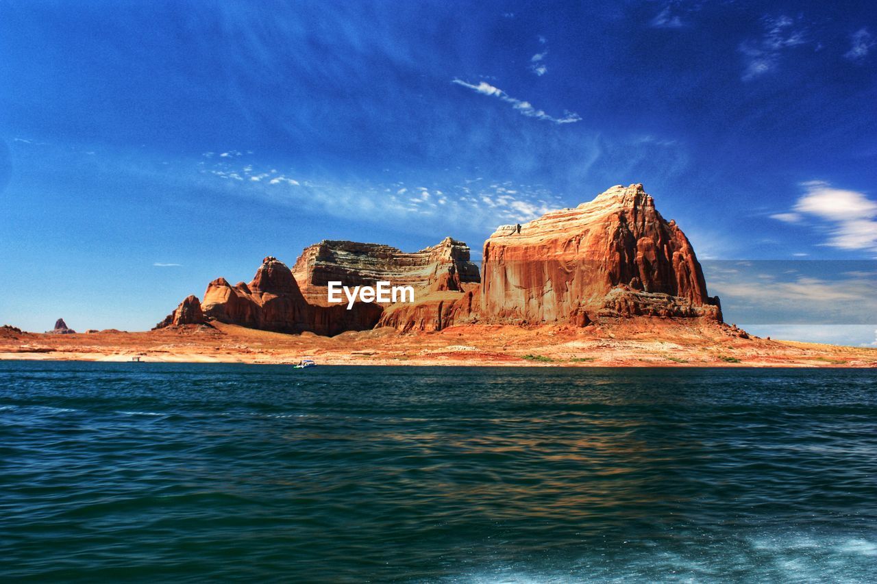 Rock formations by lake powell against blue sky