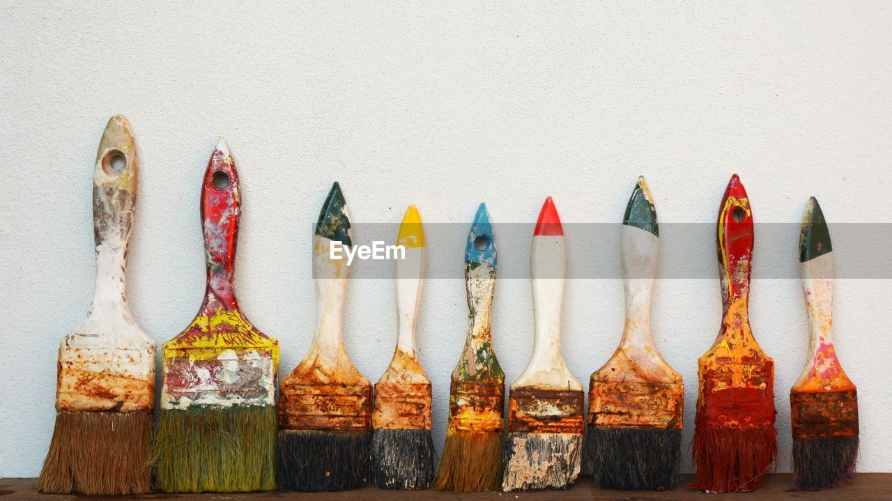 Close-up of paintbrushes against white wall