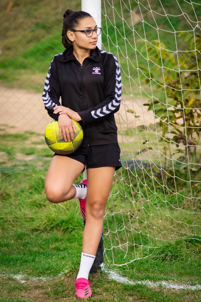 sports, one person, clothing, full length, grass, sports clothing, women, athlete, lifestyles, adult, ball, young adult, player, nature, leisure activity, child, plant, standing, day, female, exercising, outdoors, footwear, sports equipment, front view, green, person, teenager, soccer, team sport, shoe, glasses