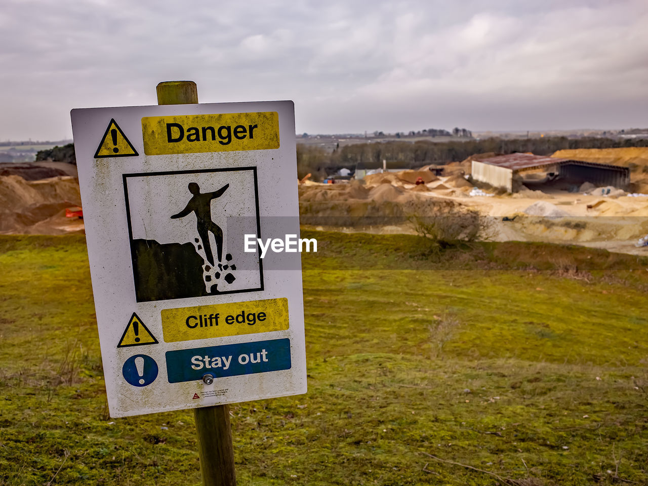 Warning sign on field against sky