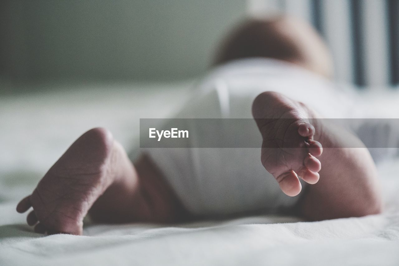 Low section of baby boy relaxing on bed