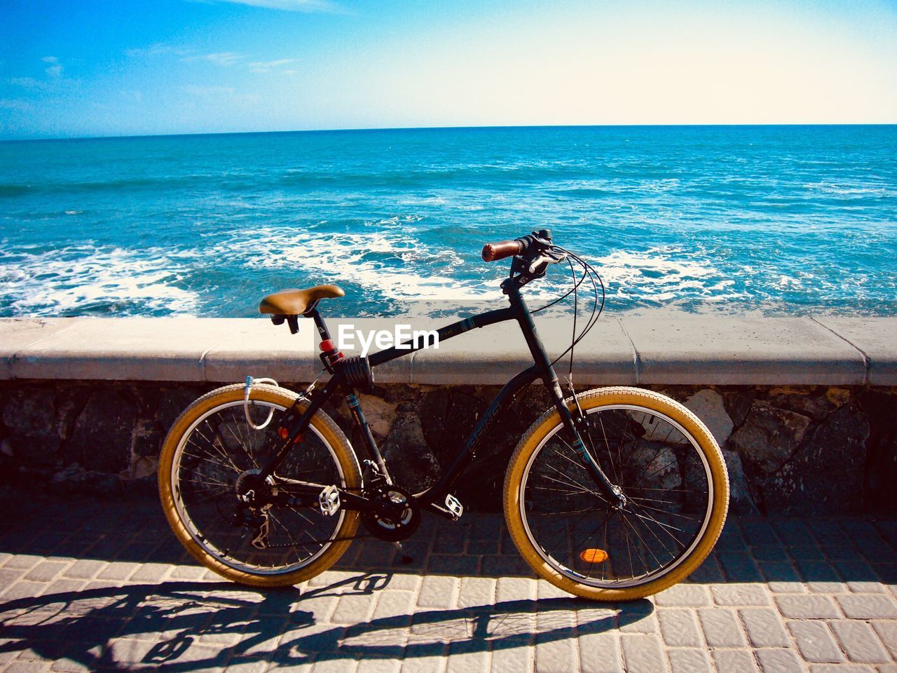 Bicycle by sea against sky