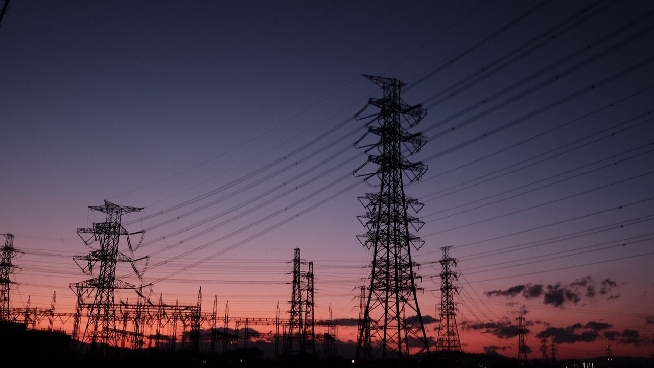 Low angle view of electricity pylon against cloudy sky