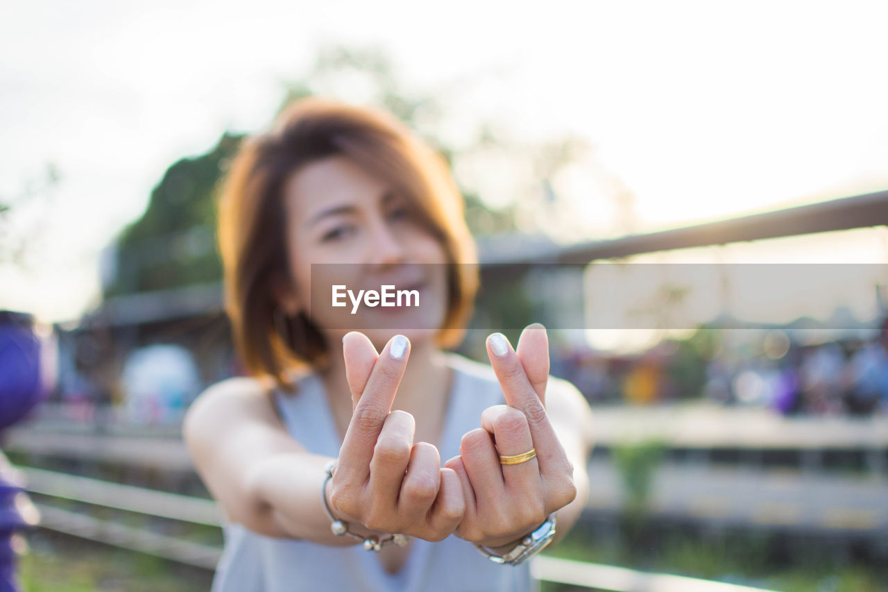 Close-up of woman gesturing standing against sky