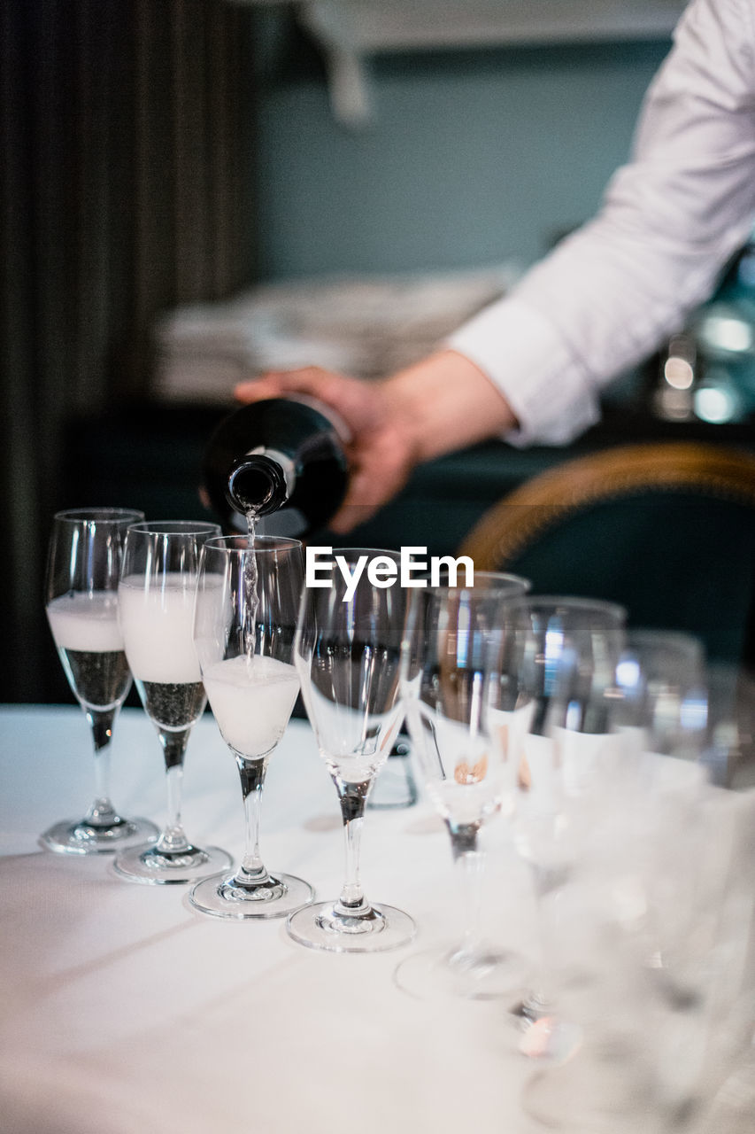 Midsection of man pouring drinks in glass on table