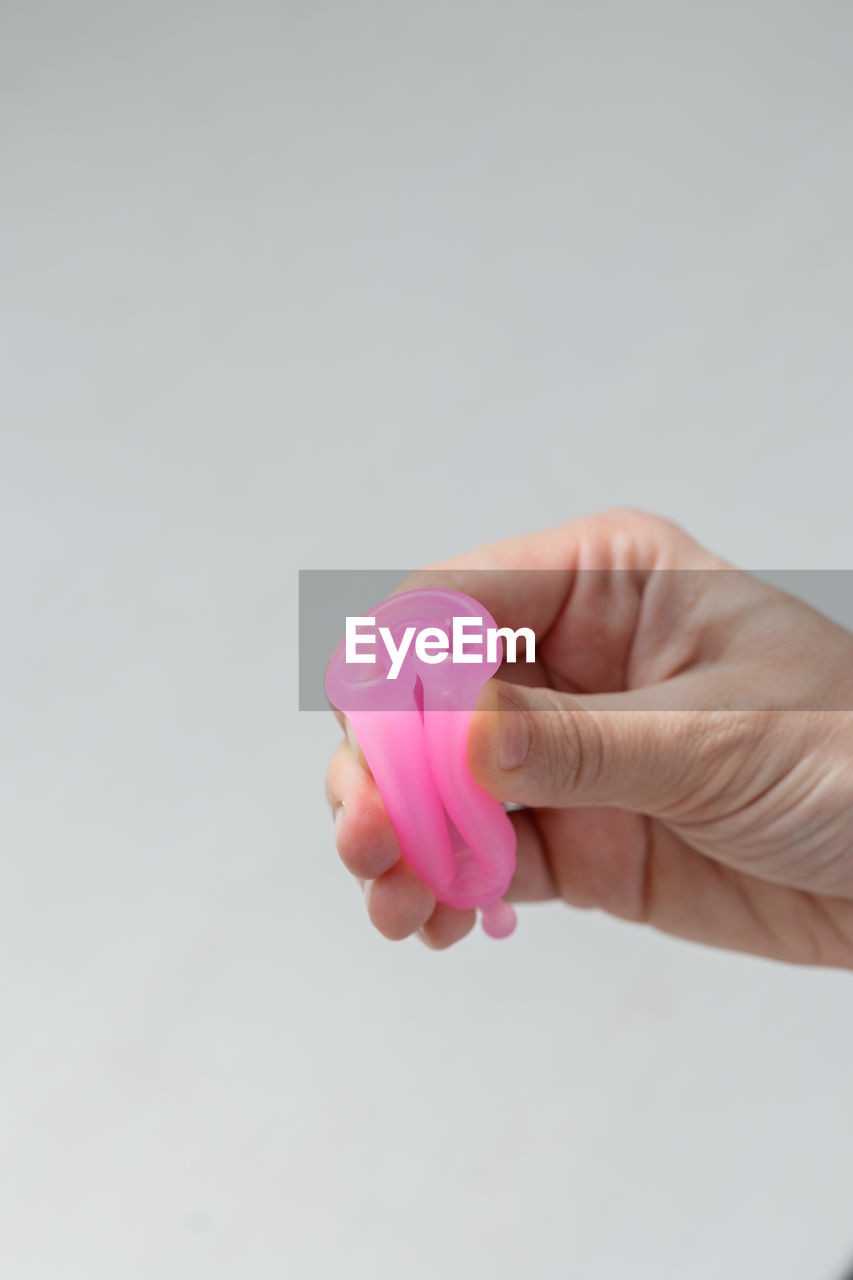 Cropped hand of person holding heart shape against white background