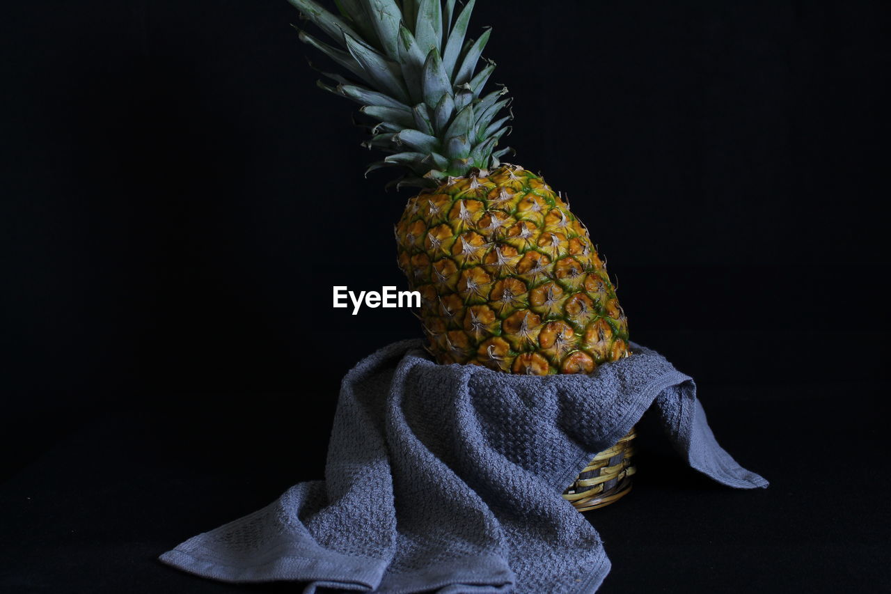 Pineapple standing in a basket and kitchen towel