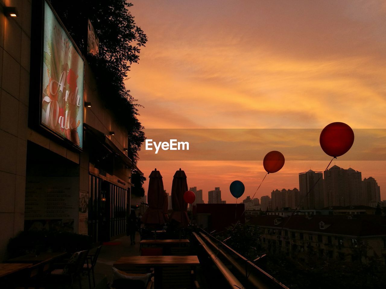 Balloons hanging at cafe against cloudy sky