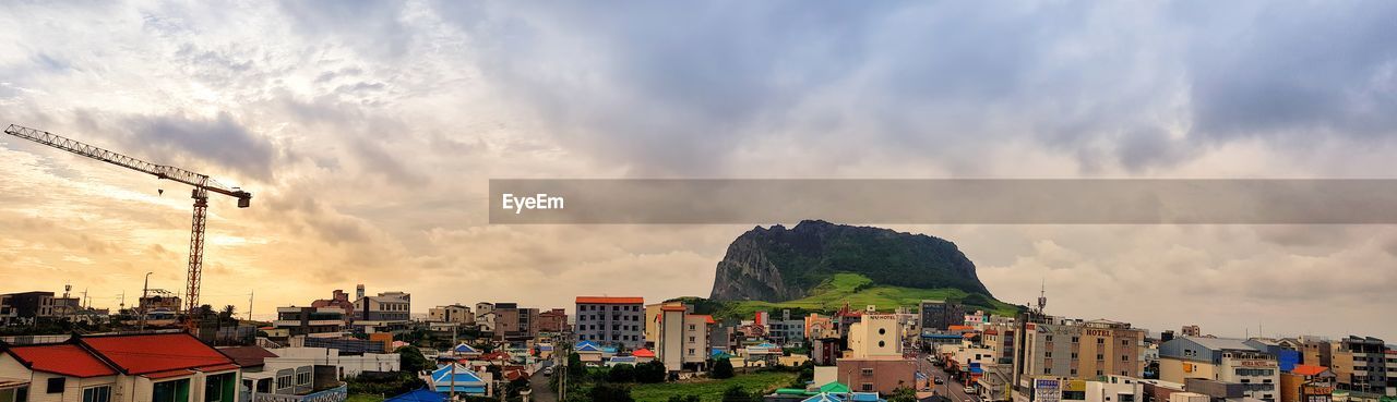 PANORAMIC VIEW OF BUILDINGS AGAINST CLOUDY SKY