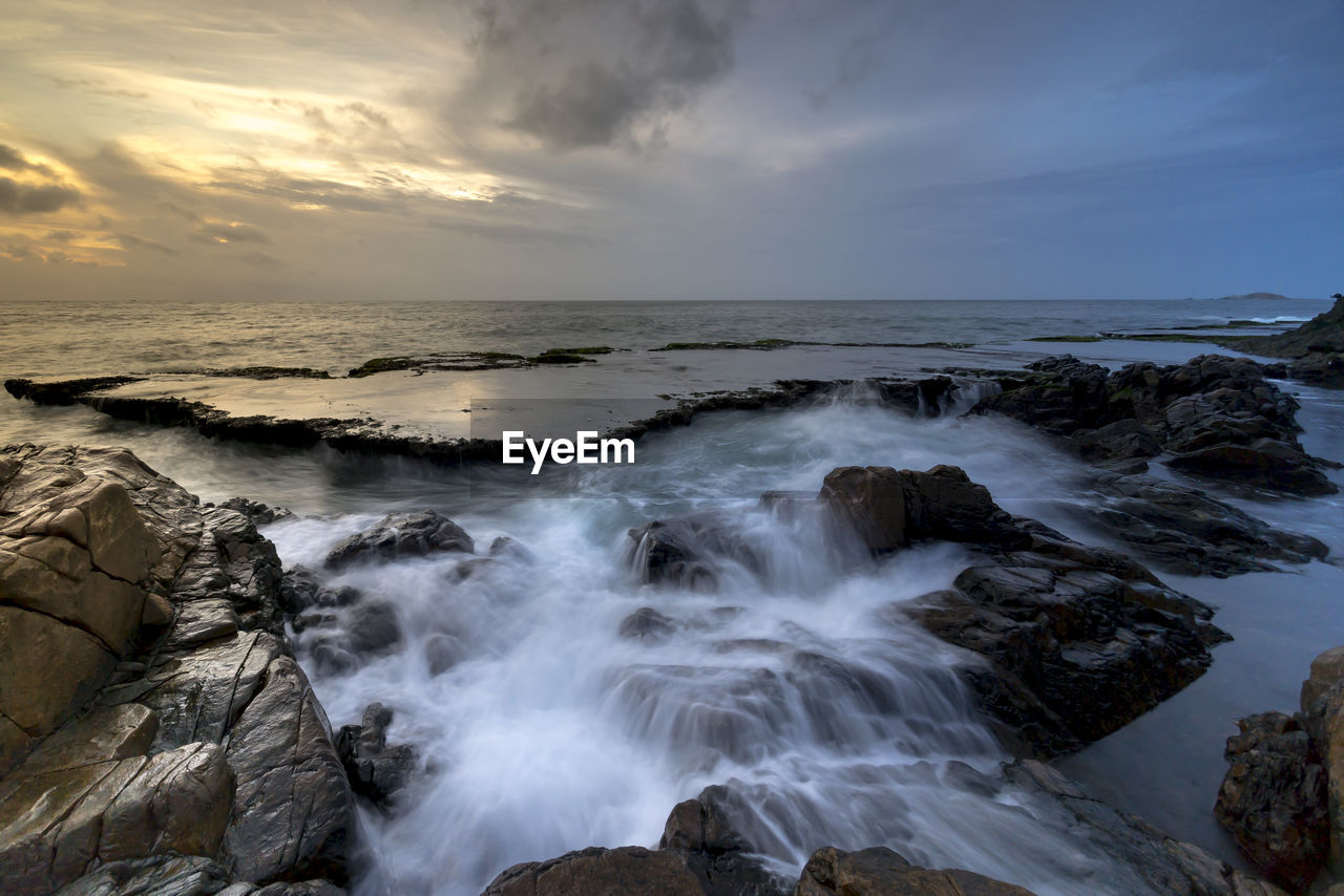 Scenic view of sea against cloudy sky during sunset