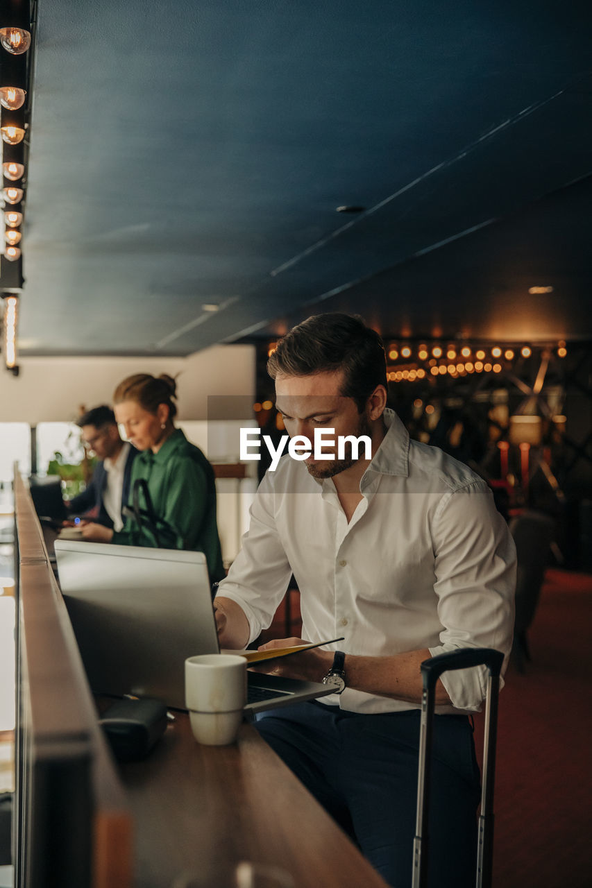 Young businessman using laptop while sitting in hotel