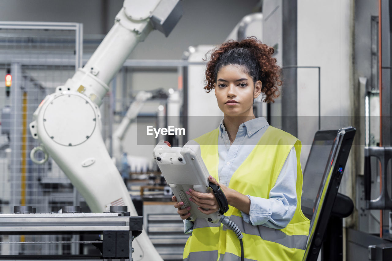 Engineer standing with equipment in front of robotic arm