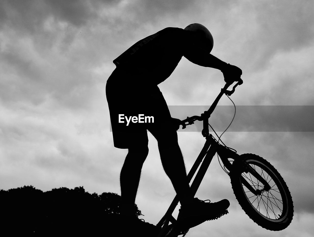 SILHOUETTE OF MAN RIDING BICYCLE AGAINST SKY